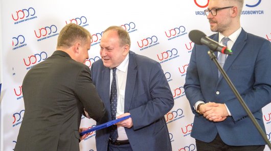 Prezes UODO Jan Nowak i wiceprezes Mirosław Sanek wręczają nagrodę dr. Grzegorzowi Sibidze.